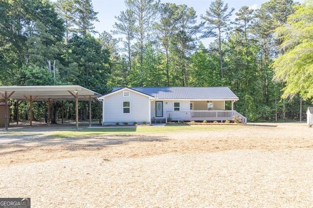 view of front of house featuring a detached carport, dirt driveway, metal roof, and a porch