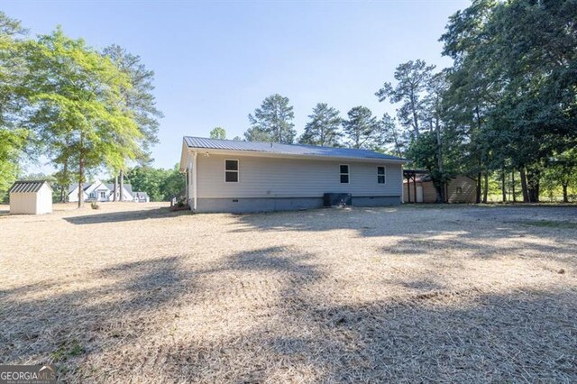 view of front of house featuring covered porch, an outbuilding, driveway, a carport, and view of wooded area