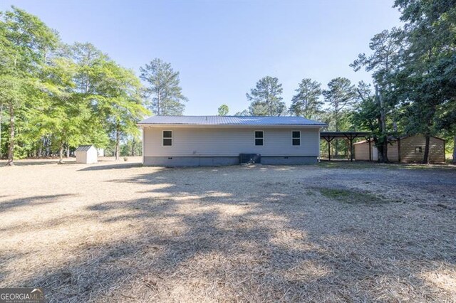 rear view of house featuring a storage unit, crawl space, an outdoor structure, and metal roof