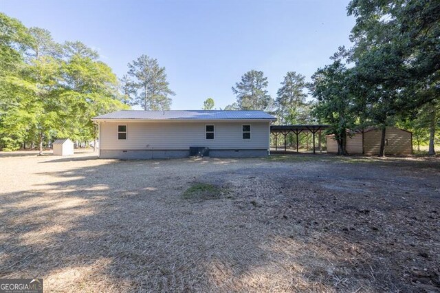 rear view of house with a storage shed, an outdoor structure, crawl space, and central AC