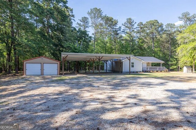 view of car parking featuring a storage unit, a carport, a garage, and driveway