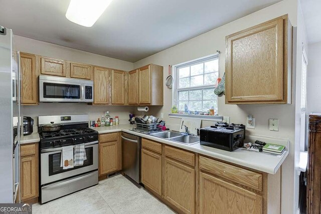 kitchen with appliances with stainless steel finishes, a sink, and light countertops
