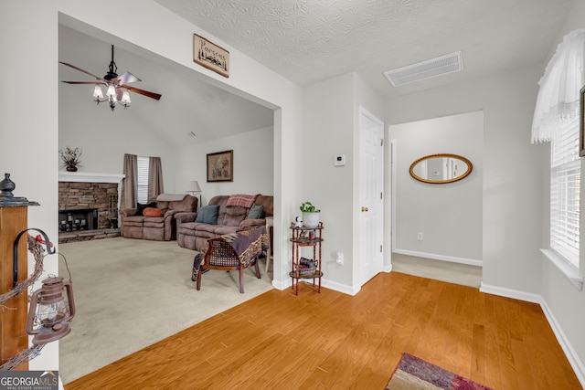 living room featuring a ceiling fan, light wood-style flooring, baseboards, and a fireplace