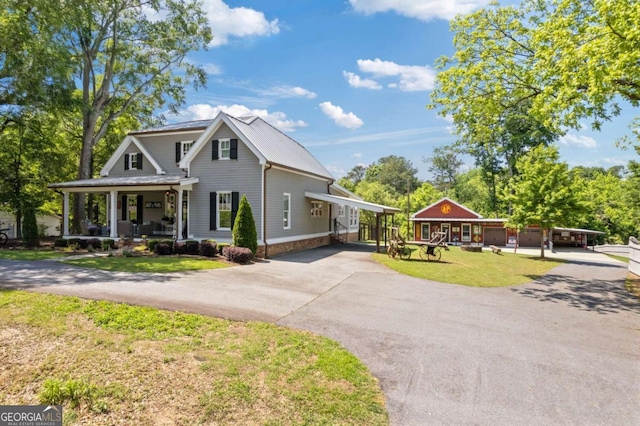 view of front of house with asphalt driveway, a porch, a front yard, and metal roof