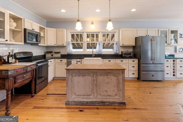 kitchen featuring appliances with stainless steel finishes, a center island, tasteful backsplash, a sink, and open shelves