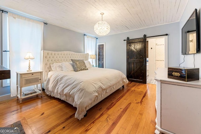 bedroom featuring a barn door, light wood-style floors, crown molding, and wooden ceiling