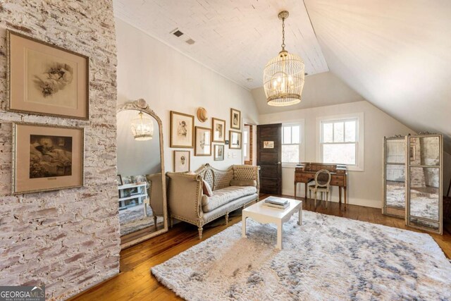 living area with vaulted ceiling, a chandelier, and wood finished floors
