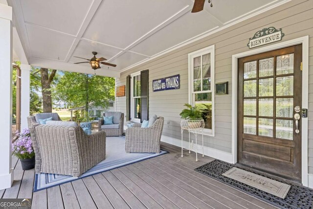 wooden terrace featuring a ceiling fan, covered porch, and outdoor lounge area