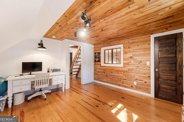 office space featuring lofted ceiling, wood walls, wood finished floors, and baseboards