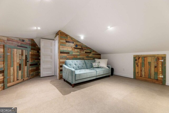 living area featuring vaulted ceiling, wooden walls, and carpet floors