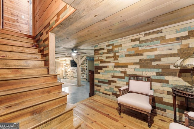living area with wood walls, stairway, wood ceiling, concrete floors, and ceiling fan