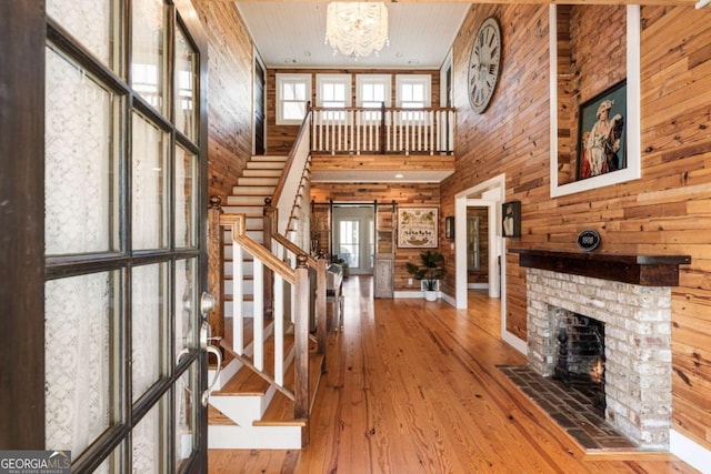 entrance foyer with stairway, healthy amount of natural light, wood walls, a high ceiling, and a chandelier
