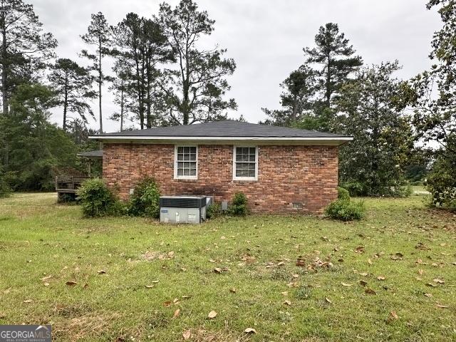 rear view of property featuring brick siding and a yard