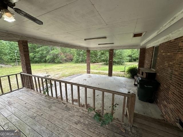 wooden deck featuring a ceiling fan and a lawn