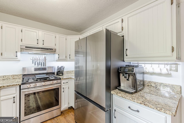 4314 Arbor Bridge Ct, Marietta, GA 30066 - kitchen with stainless steel appliances, under cabinet range hood, a textured ceiling, light wood-style flooring, and light stone countertops
