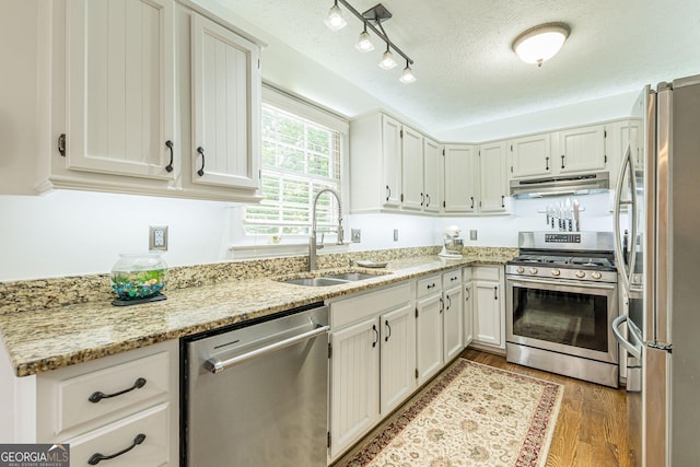4314 Arbor Bridge Ct, Marietta, GA 30066 - kitchen with appliances with stainless steel finishes, under cabinet range hood, a textured ceiling, light wood-style floors, and light stone counters