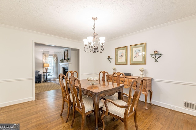 4314 Arbor Bridge Ct, Marietta, GA 30066 - dining room with a chandelier, ornamental molding, light wood finished floors, a textured ceiling, and a fireplace