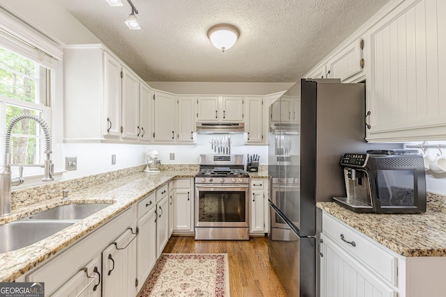 4314 Arbor Bridge Ct, Marietta, GA 30066 - kitchen featuring stainless steel appliances, under cabinet range hood, a textured ceiling, wood finished floors, and white cabinets