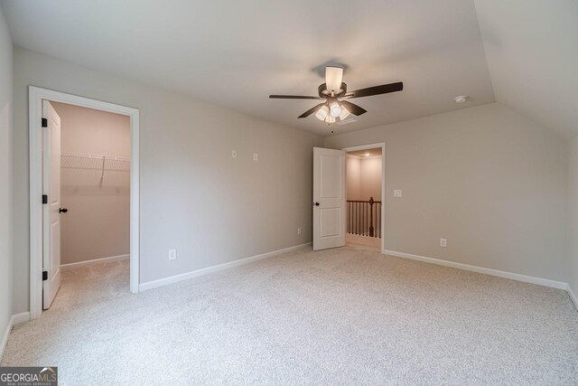 1482 Alcovy Station Rd, Covington, GA 30014 - unfurnished bedroom featuring light colored carpet, a walk in closet, ceiling fan, baseboards, and lofted ceiling