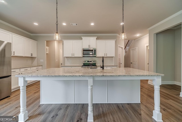 1482 Alcovy Station Rd, Covington, GA 30014 - kitchen with appliances with stainless steel finishes, ornamental molding, wood finished floors, tasteful backsplash, and white cabinets
