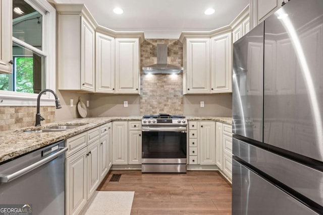 3232 Cates Ave NE, Brookhaven, GA 30319 - kitchen featuring appliances with stainless steel finishes, wall chimney range hood, light wood-type flooring, tasteful backsplash, and light stone counters