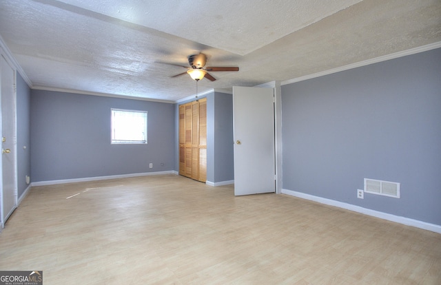 unfurnished bedroom featuring crown molding, a textured ceiling, light wood-style floors, baseboards, and ceiling fan