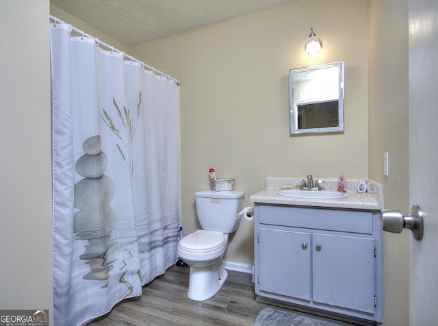 bathroom featuring toilet, wood finished floors, vanity, and curtained shower