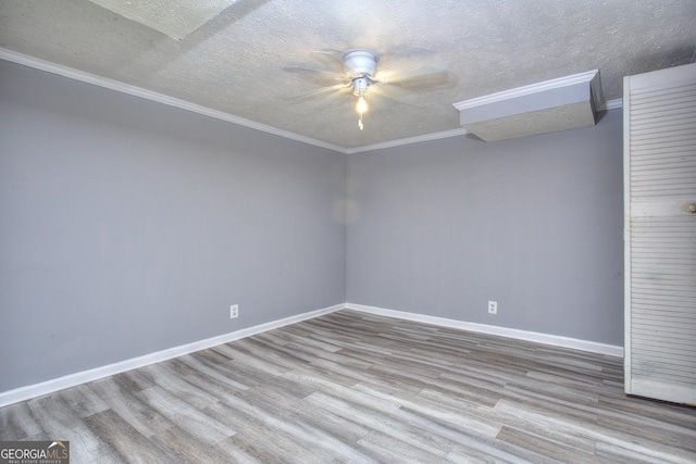 empty room with ceiling fan, wood finished floors, crown molding, a textured ceiling, and baseboards