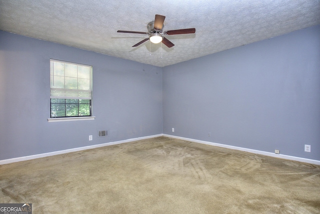 carpeted spare room with a ceiling fan, baseboards, and a textured ceiling