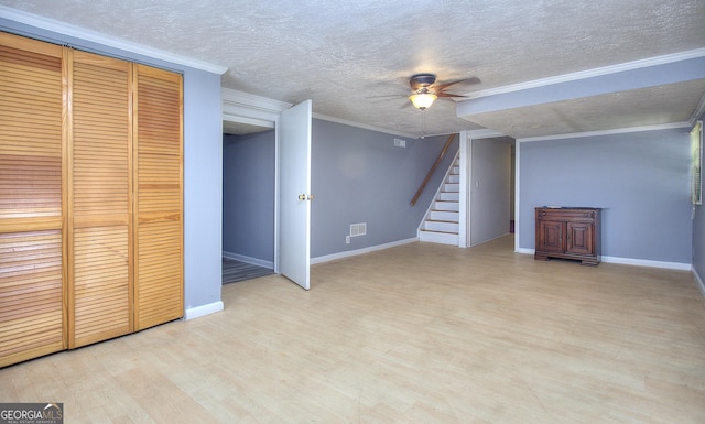 basement with a ceiling fan, light wood-style floors, a textured ceiling, stairway, and baseboards