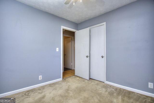unfurnished bedroom featuring carpet flooring, baseboards, a ceiling fan, a textured ceiling, and a closet