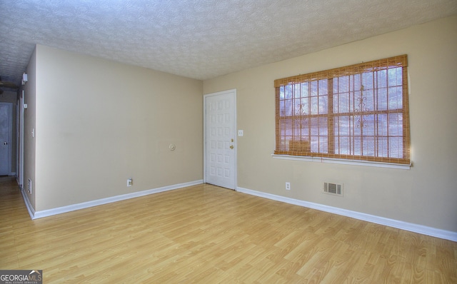 spare room featuring wood finished floors, baseboards, and a textured ceiling