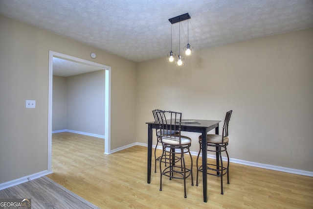 dining room with wood finished floors, a textured ceiling, and baseboards