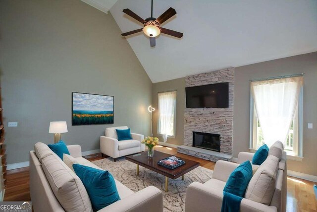 living room featuring ceiling fan, healthy amount of natural light, baseboards, and high vaulted ceiling