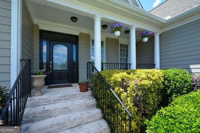 entrance to property with a porch and roof with shingles