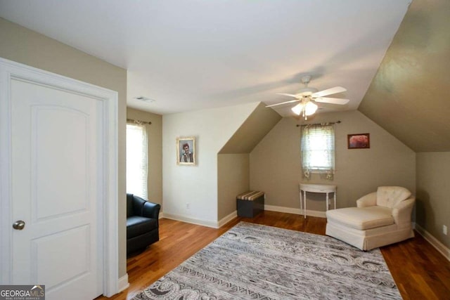 living area featuring wood finished floors, ceiling fan, baseboards, and lofted ceiling