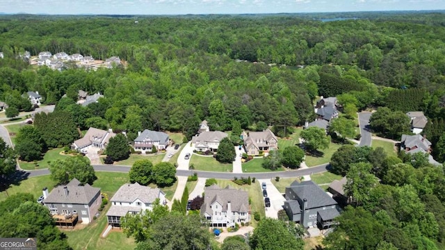 aerial view of property's location featuring a forest and nearby suburban area