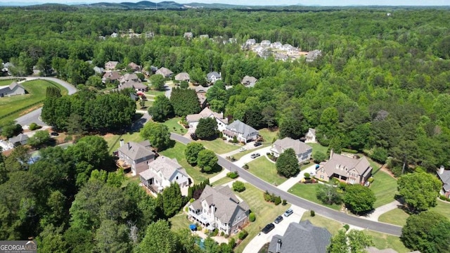 aerial view of property's location featuring a forest and nearby suburban area