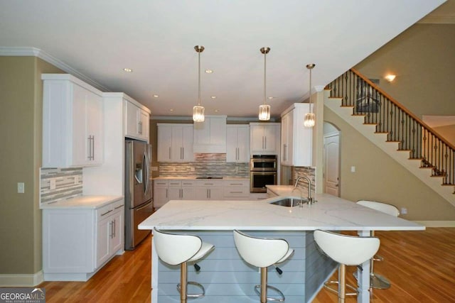 kitchen featuring appliances with stainless steel finishes, a sink, decorative backsplash, white cabinets, and recessed lighting