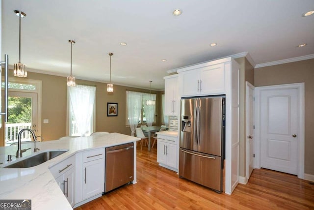 kitchen with stainless steel appliances, a sink, crown molding, light stone countertops, and white cabinetry