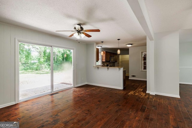 unfurnished living room with ceiling fan, dark wood finished floors, a textured ceiling, and baseboards