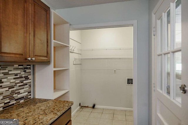 laundry area with healthy amount of natural light, washer hookup, baseboards, and light tile patterned flooring