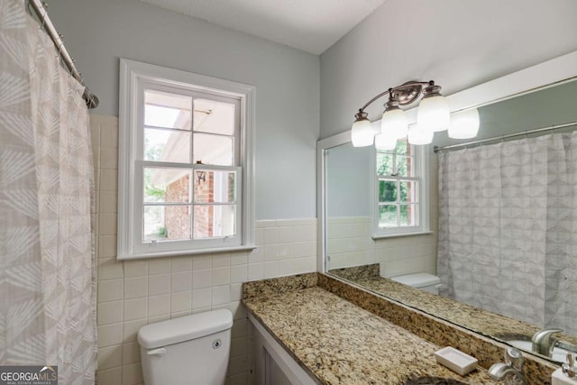 full bathroom featuring toilet, tile walls, wainscoting, and vanity