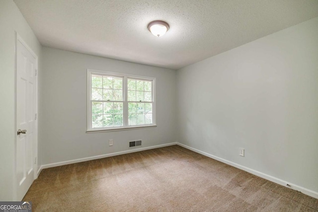 empty room featuring carpet flooring, baseboards, and a textured ceiling