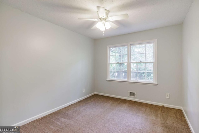 carpeted spare room with a ceiling fan, baseboards, and a textured ceiling