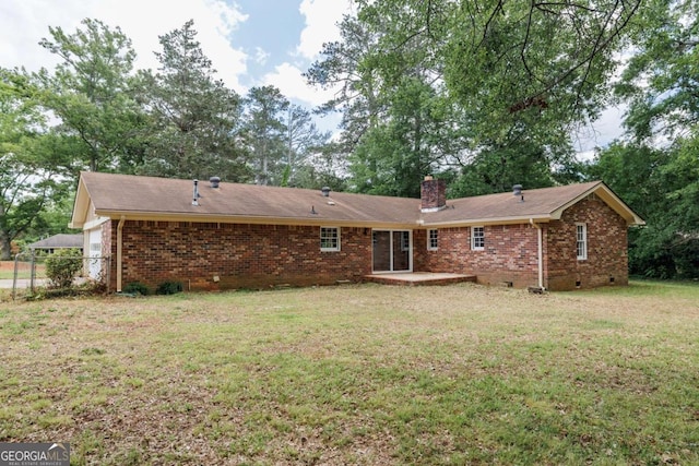 rear view of property featuring a chimney, brick siding, a patio, and crawl space