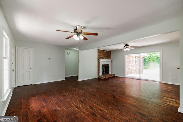 unfurnished living room with ceiling fan, hardwood / wood-style flooring, a brick fireplace, and baseboards