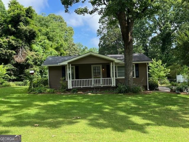 ranch-style house featuring covered porch and a front lawn