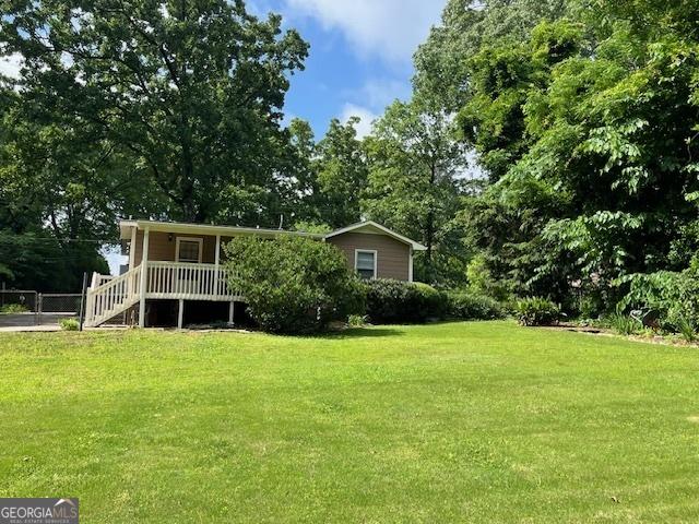 view of front of home with a front lawn and view of wooded area