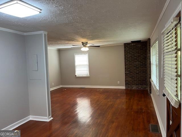 unfurnished room featuring a textured ceiling, wood finished floors, a ceiling fan, baseboards, and ornamental molding